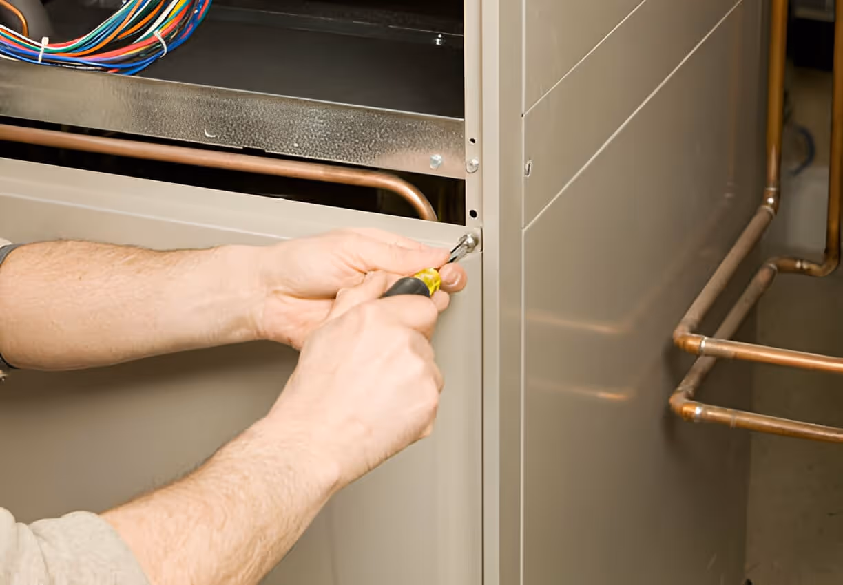 Technician using screwdriver to repair electrical equipment with copper pipes