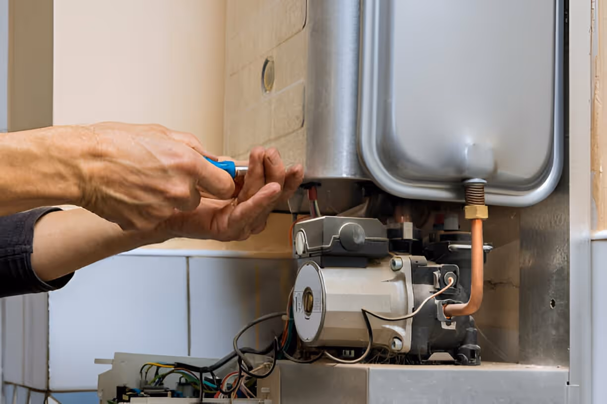 Technician repairing water heater with blue-handled screwdriver