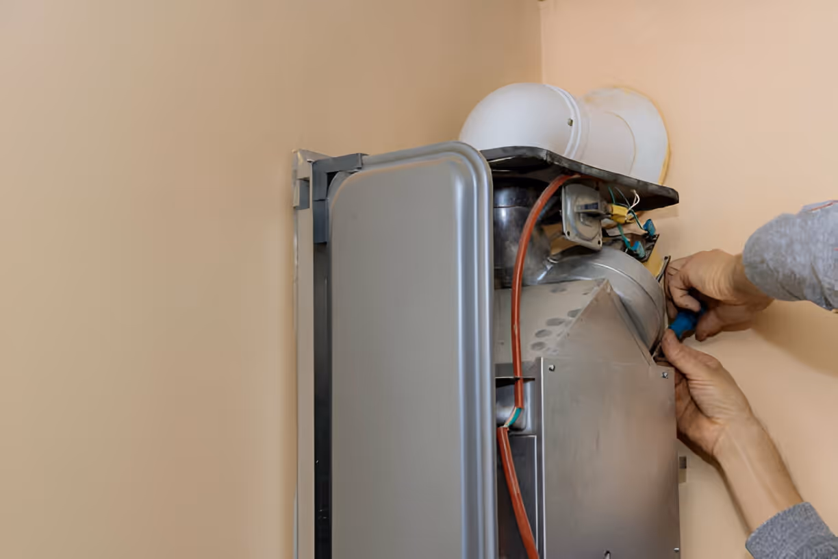 Technician repairing an electric water heater with exposed internal components