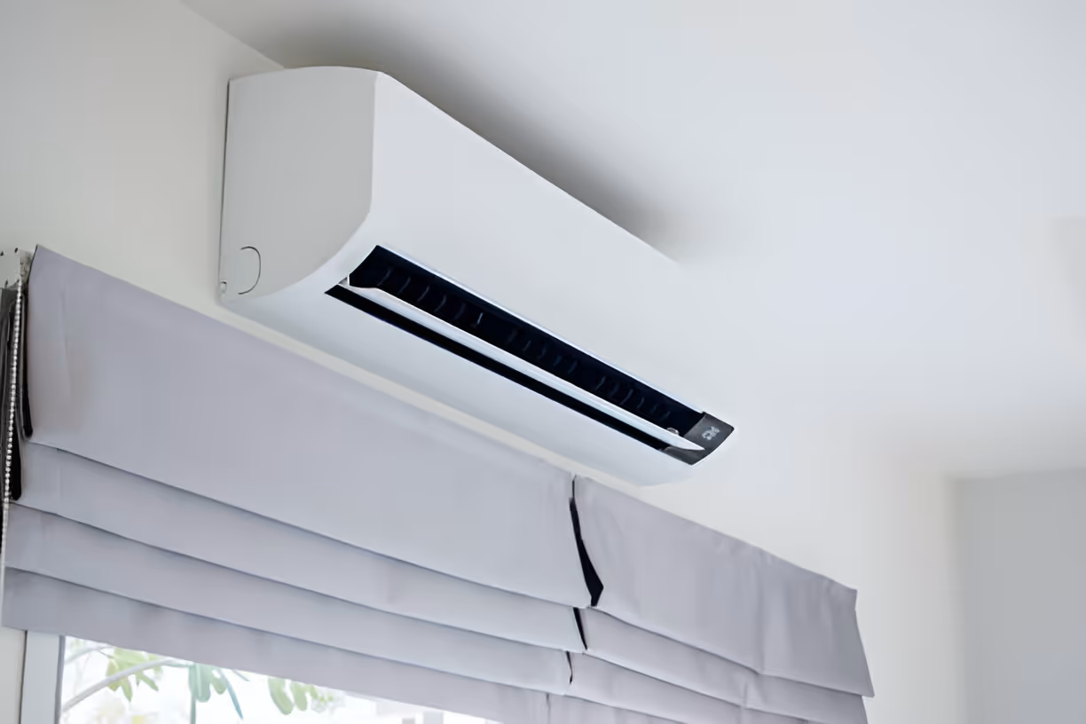 White air conditioning unit mounted on wall above window blinds