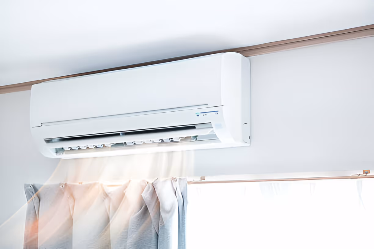 White air conditioning unit mounted on wall above soft curtains