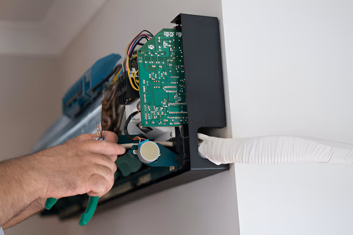 Technician repairing circuit board with green pliers and white glove