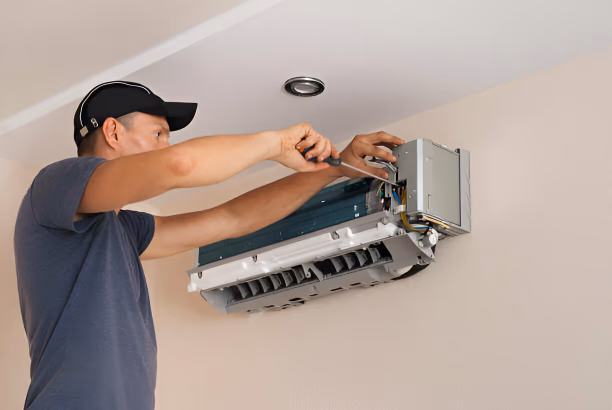 Technician installing air conditioning unit on wall with screwdriver
