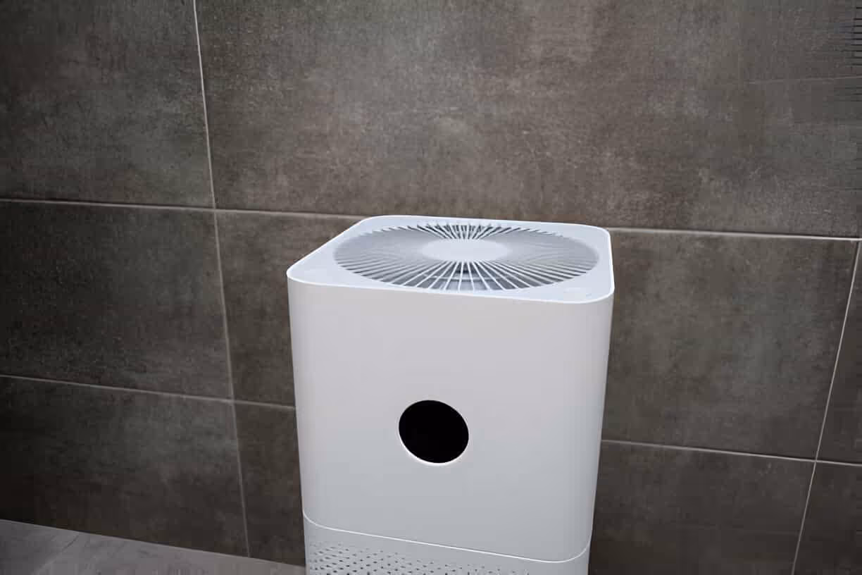 White air purifier with circular fan design against gray tiled wall