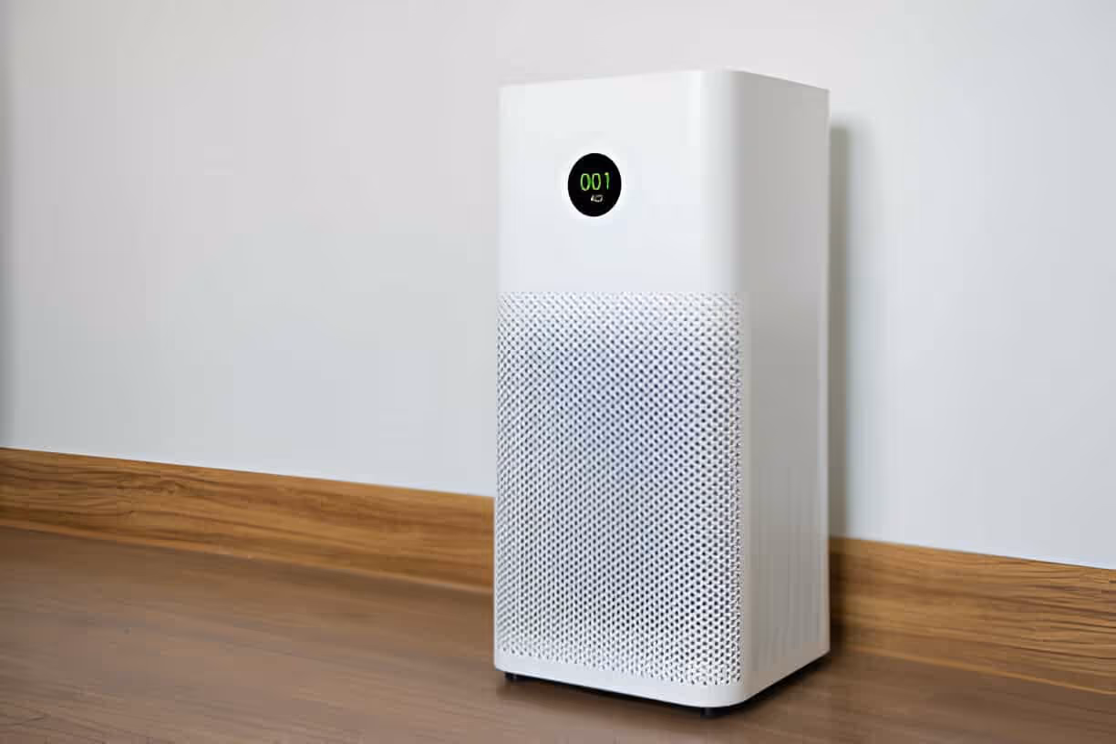 White air purifier with digital display on wooden floor against white wall