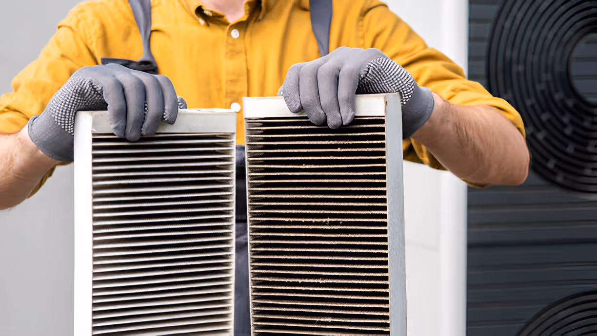 Person comparing clean and dirty air filters in yellow shirt