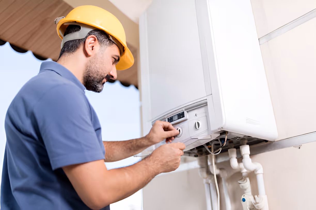 Technician in hard hat repairing or checking electrical panel or water heater