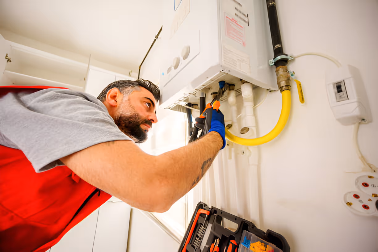 Technician repairing water heater with tools in residential setting