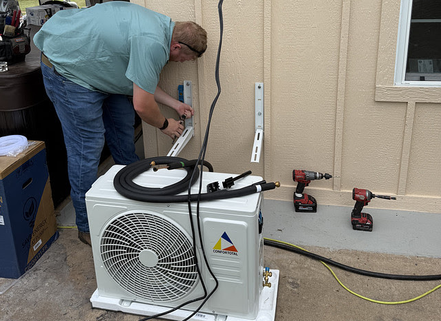 Two workers installing air conditioning unit on white wall