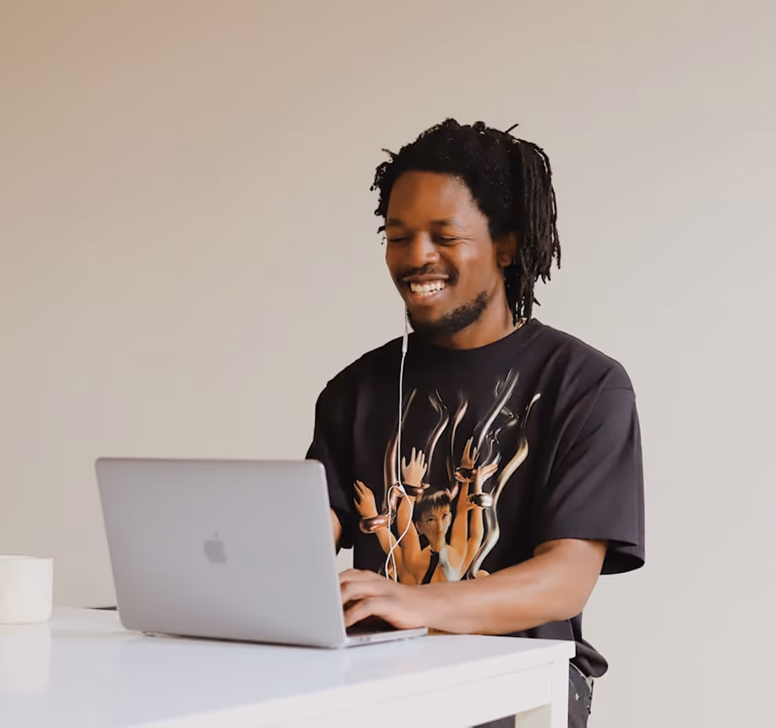 Smiling man working on a laptop, representing a creator building his brand and growing his online presence with Kicksti.