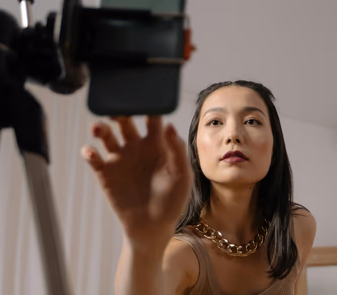 Confident woman adjusting phone on tripod, preparing to record content, representing creators using Kicksti to grow their audience.