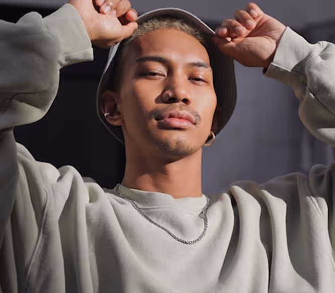 Confident male model in urban outfit posing outdoors, showcasing individuality and visual identity for social media growth.