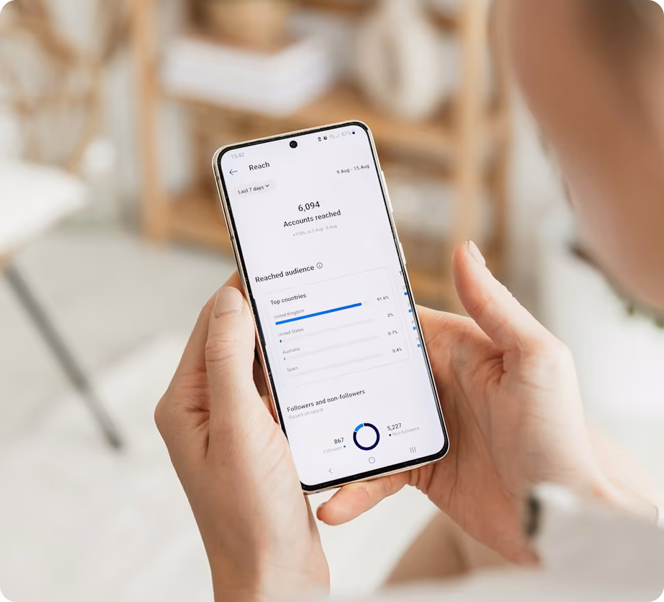 Woman analyzing Instagram reach insights on her phone, showcasing audience demographics and follower engagement through Kicksti.
