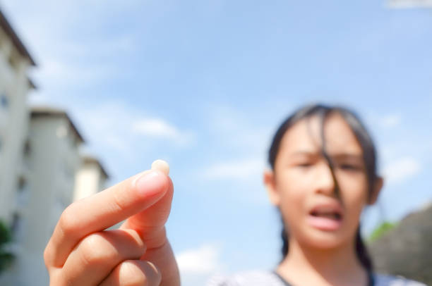 Falling milk teeth A little Thai girl (9-year-old) showing her falling milk teeth in her hand. Childhood healthcare concept child holding a chipped tooth to parent stock pictures, royalty-free photos & images