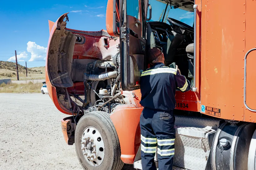 Technician performs Arizona repairs on a semi-truck with the hood raised and driver door open.