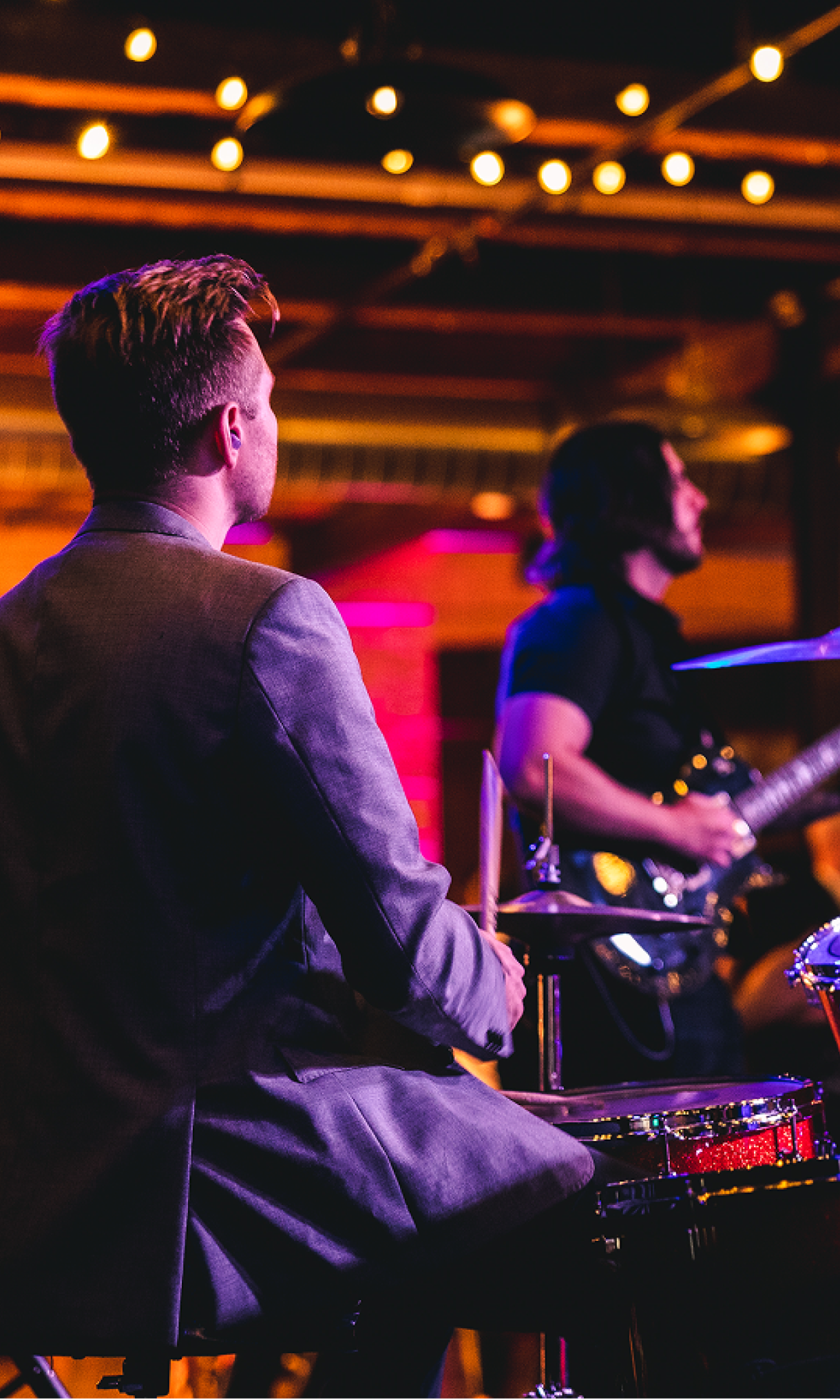 Three musicians playing instruments on a stage under warm lighting