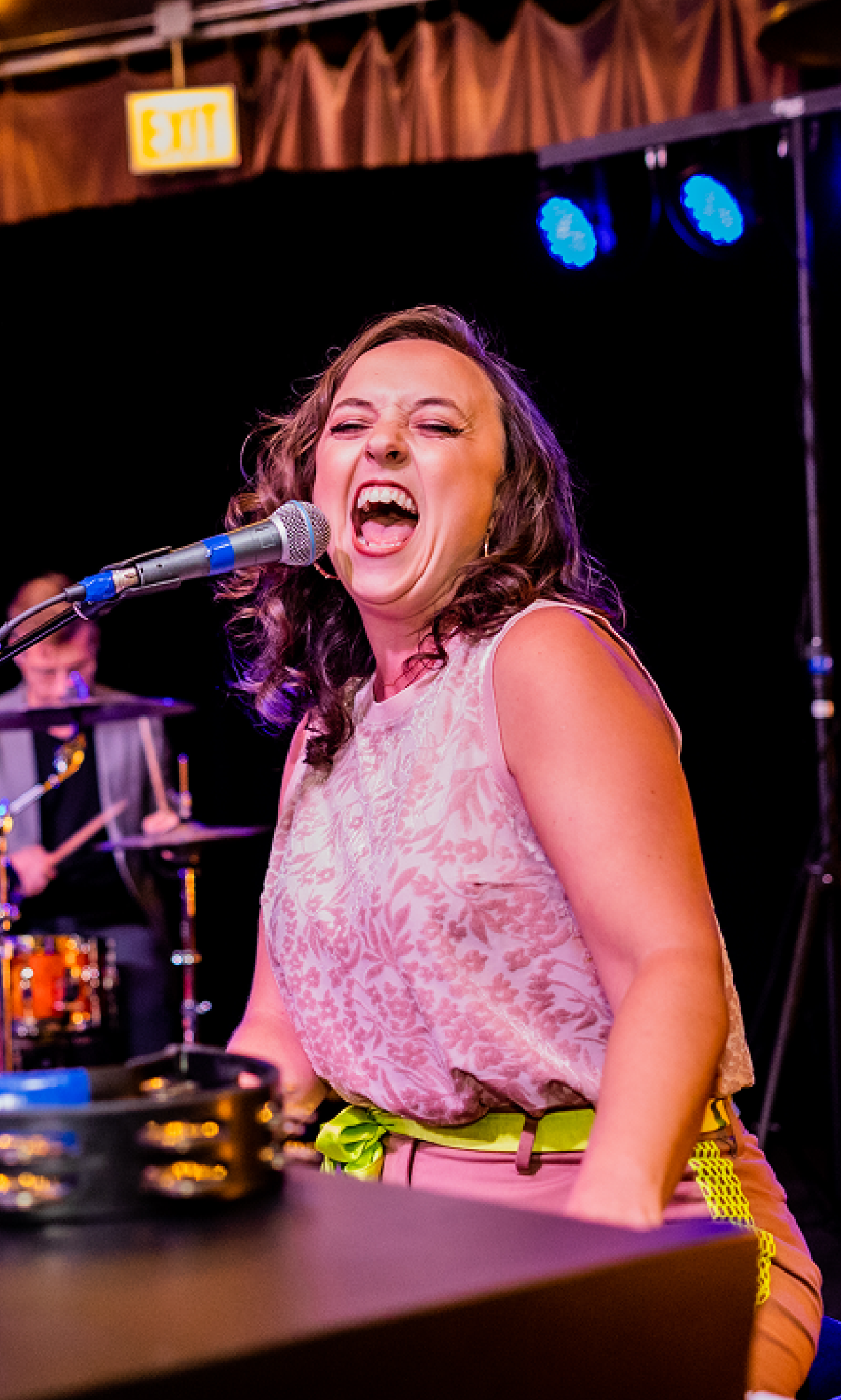Woman playing piano and singing into microphone