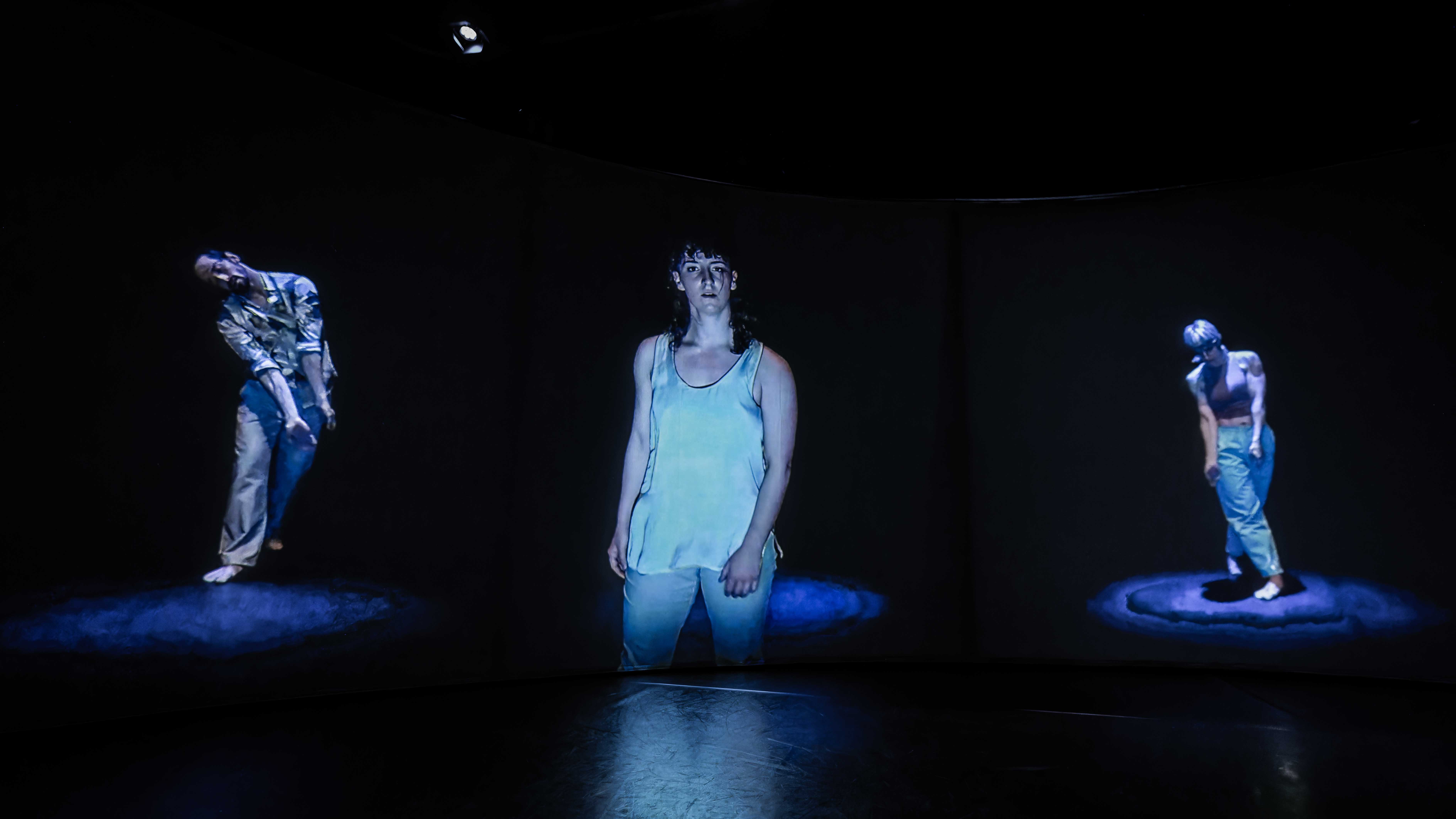 Plan rapproché de l'installation de Choeur montrant la projection des interprètes Christopher LaPlante, Cara Roy, et Sophie Breton