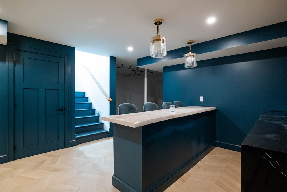 Custom live edge wood bar with tv, shelves, mirror backing, tile wall, and seating in basement remodel by JW Design | Build