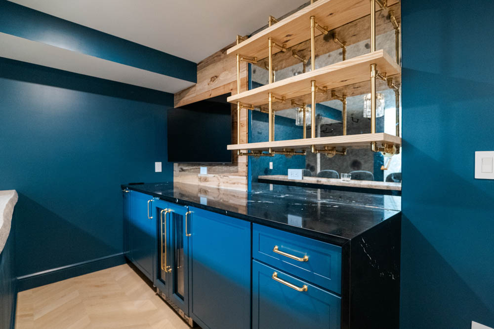Custom live edge wood bar with tv, shelves, mirror backing, tile wall, and seating in basement remodel by JW Design | Build