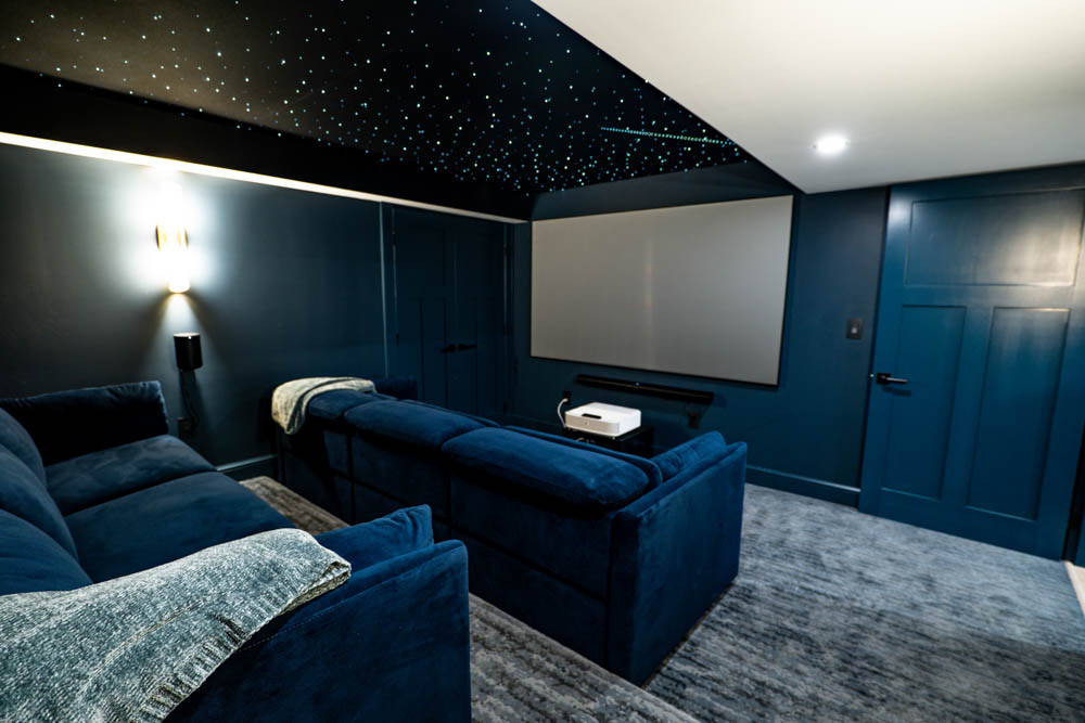 Custom home theater with starry night lit ceiling and stadium seating couches in basement remodel by JW Design | Build