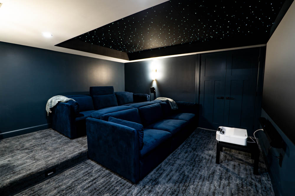 Custom home theater with starry night lit ceiling and stadium seating couches in basement remodel by JW Design | Build