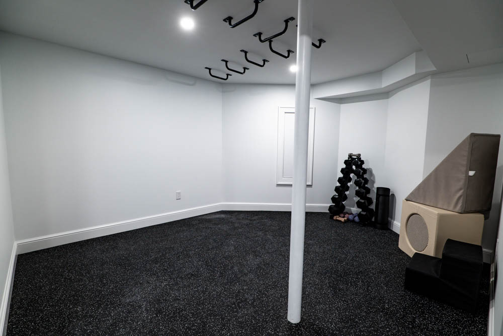 Home gym/workout area with rubber floor in basement remodel by JW Design | Build