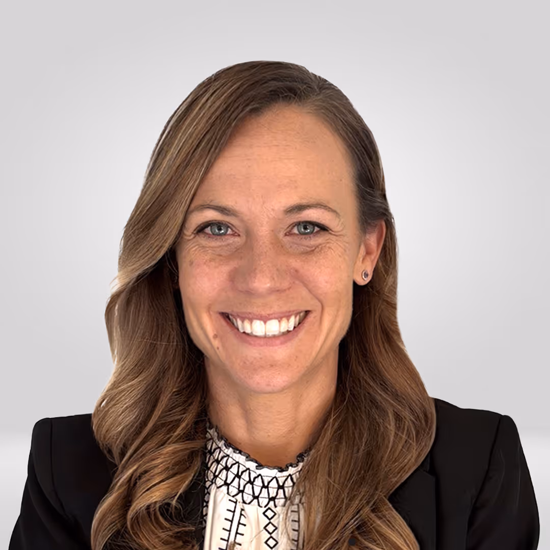 Smiling woman with long light brown hair wearing a black blazer and patterned white blouse.