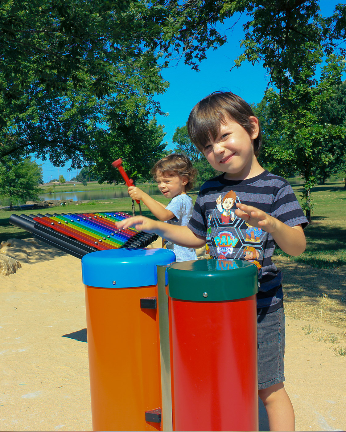 Children playing colorful outdoor musical instruments at a playground.