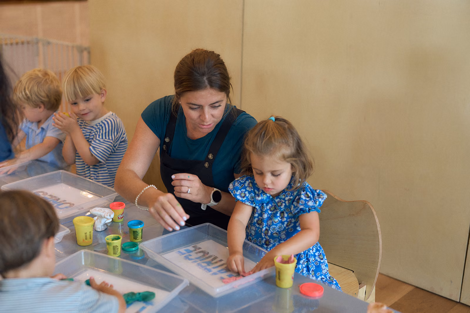 A Kinry camp educator helping a young camper with a play dough activity