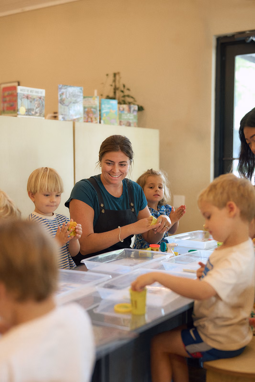A smiling educator playing with campers at the activity table
