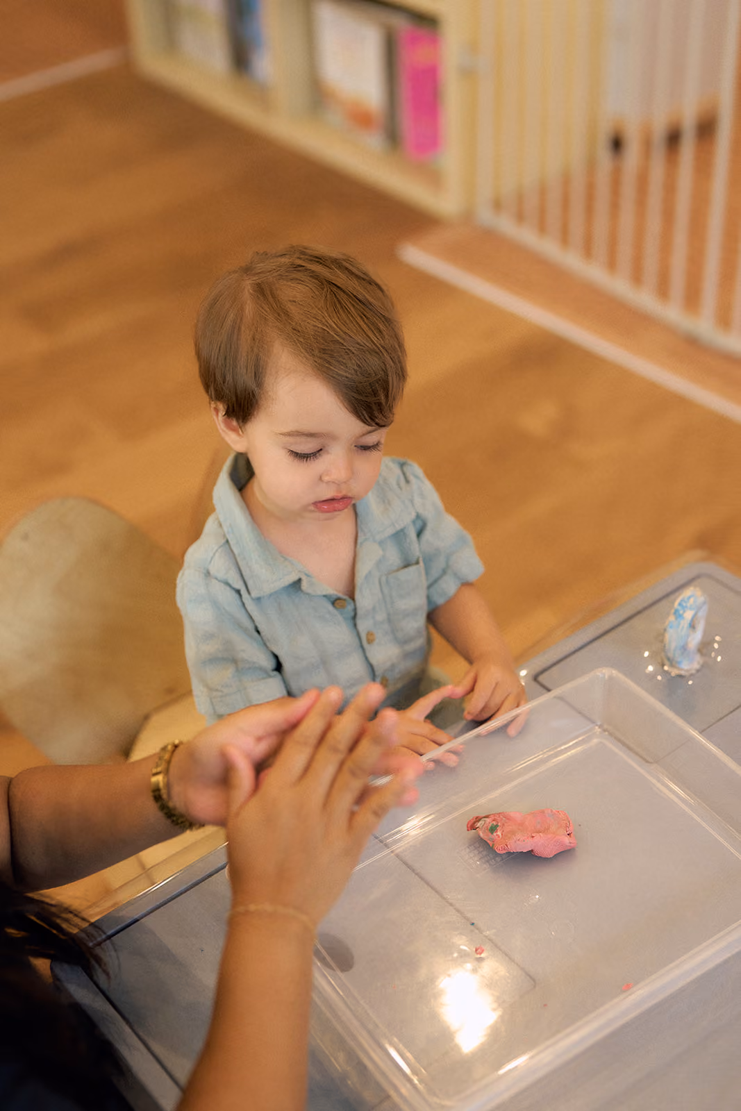 A young camper shaping play dough with an educator