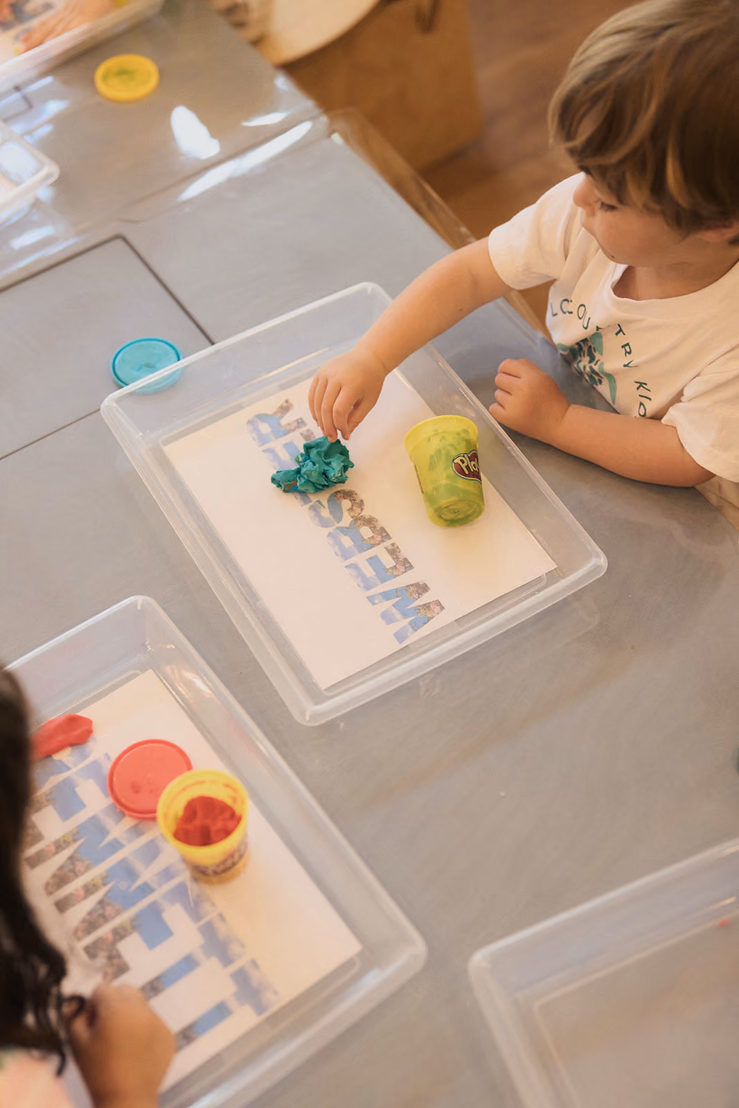 A camper pressing play dough onto a letter mat
