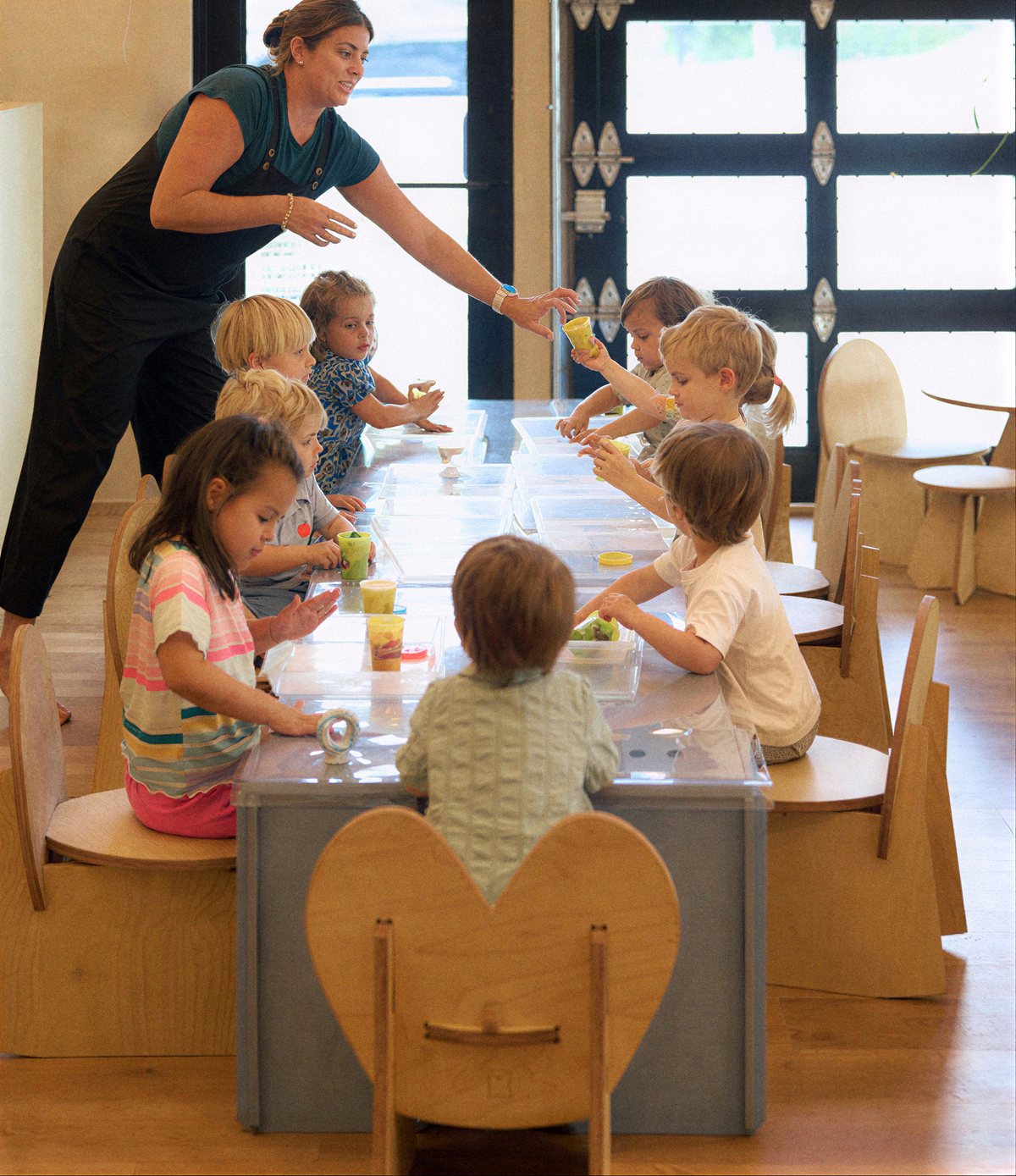 Children working at a classroom table with a Kinry teacher