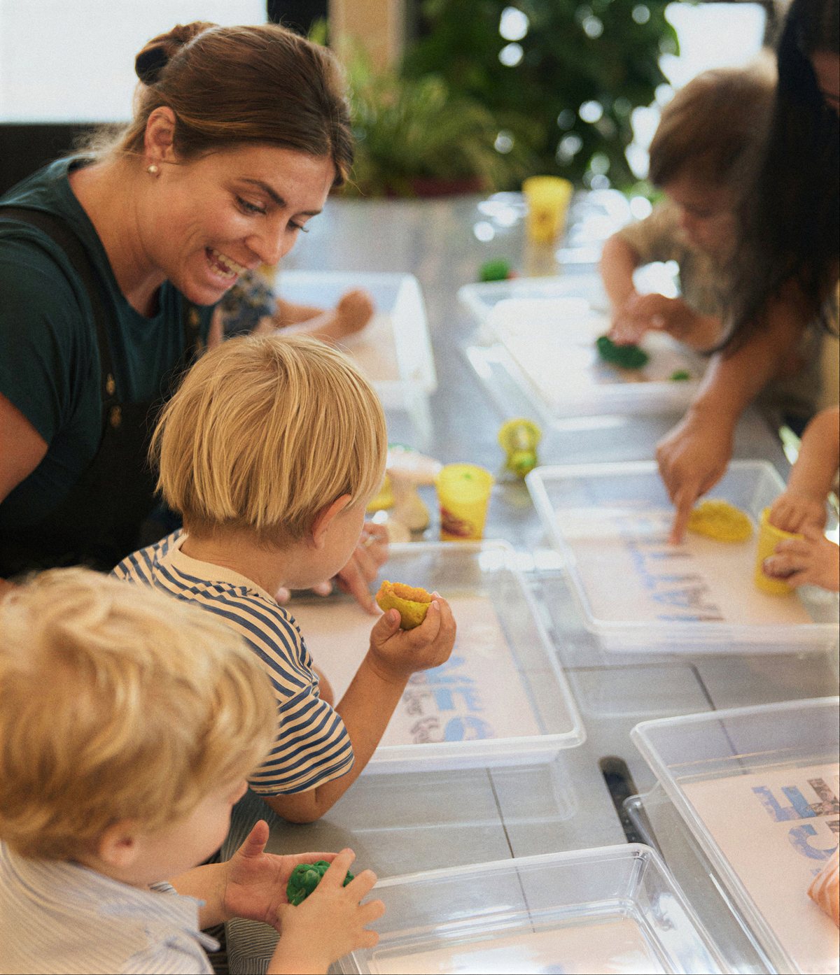 Children shaping play dough over letter cards with a Kinry teacher