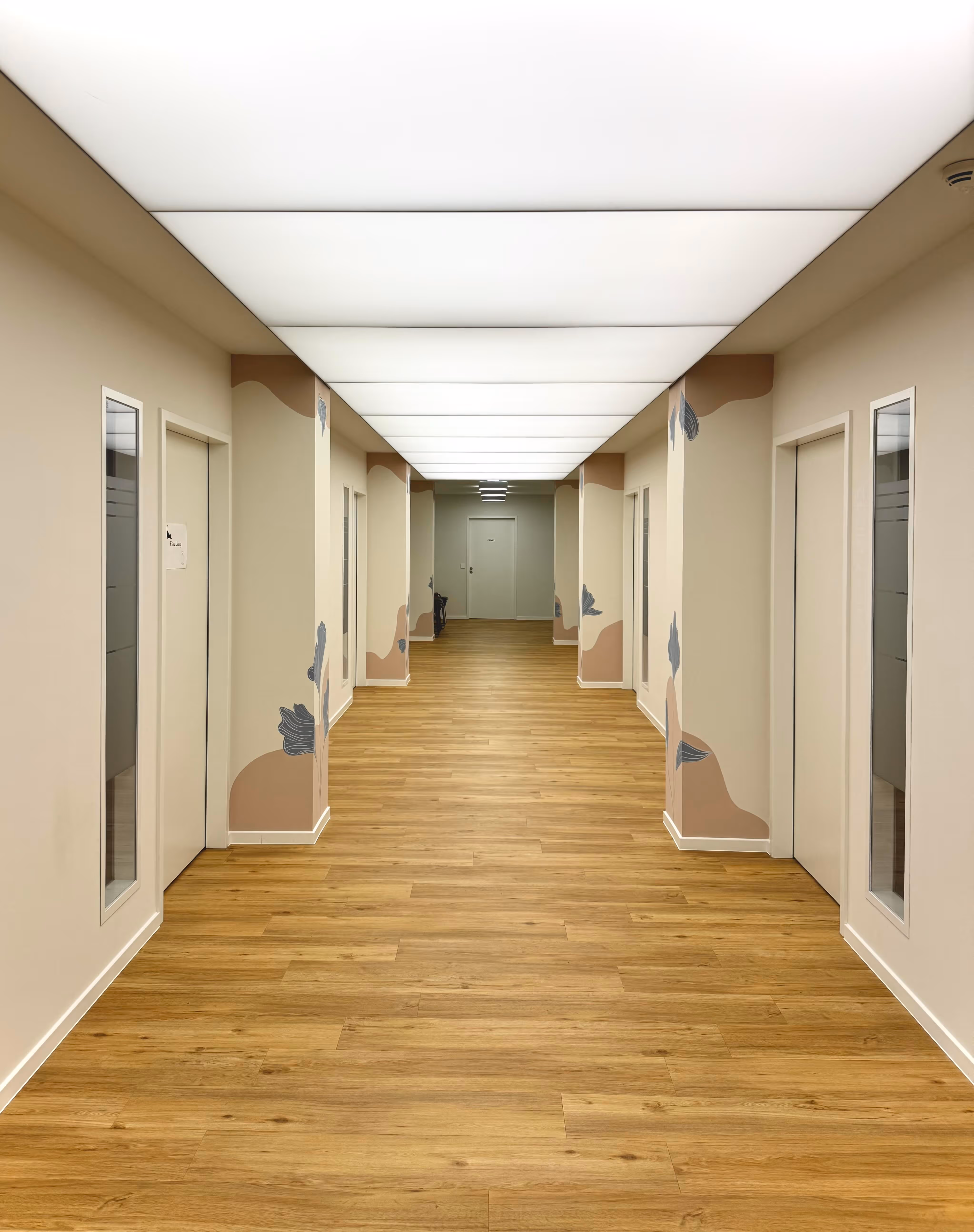 Langer Praxisflur mit Holzfußboden und durchgehender Deckenbeleuchtung.
