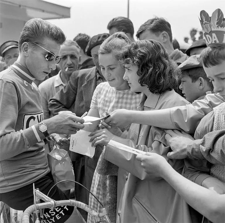 Jacques Anquetil, legendary French cyclist, signs autographs for a group of women while wearing Solamor sunglasses.