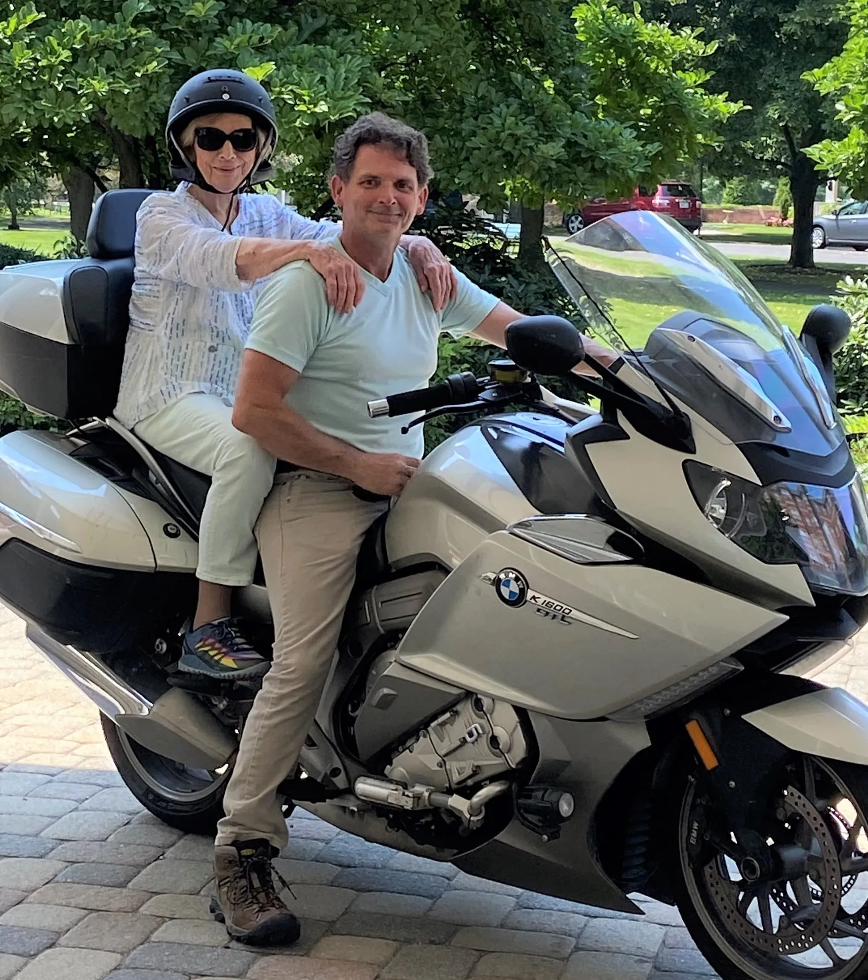 A Laurelmead resident sits on the back of a BMW touring motorcycle, smiling confidently with helmet on, ready for a ride. The scene captures a sense of adventure and vitality in the community.