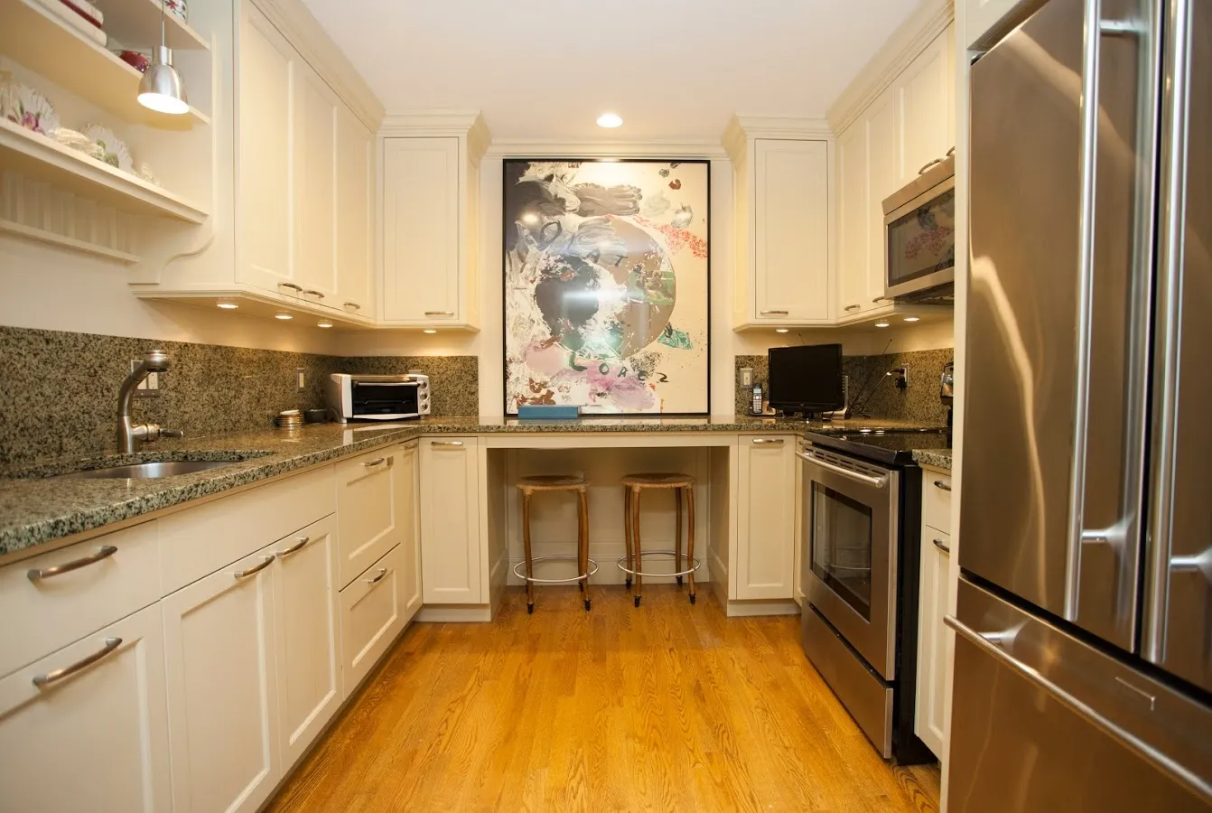 A well-appointed kitchen at Laurelmead features cream cabinetry, stainless steel appliances, granite countertops, and a unique art piece above a cozy dining nook. The space blends function with elegance, ideal for everyday living.