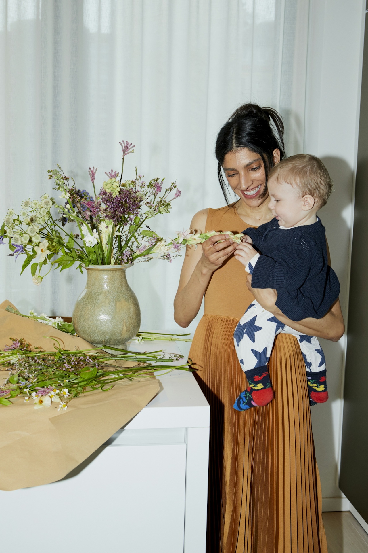 Mother holding a toddler on her hip while arranging flowers