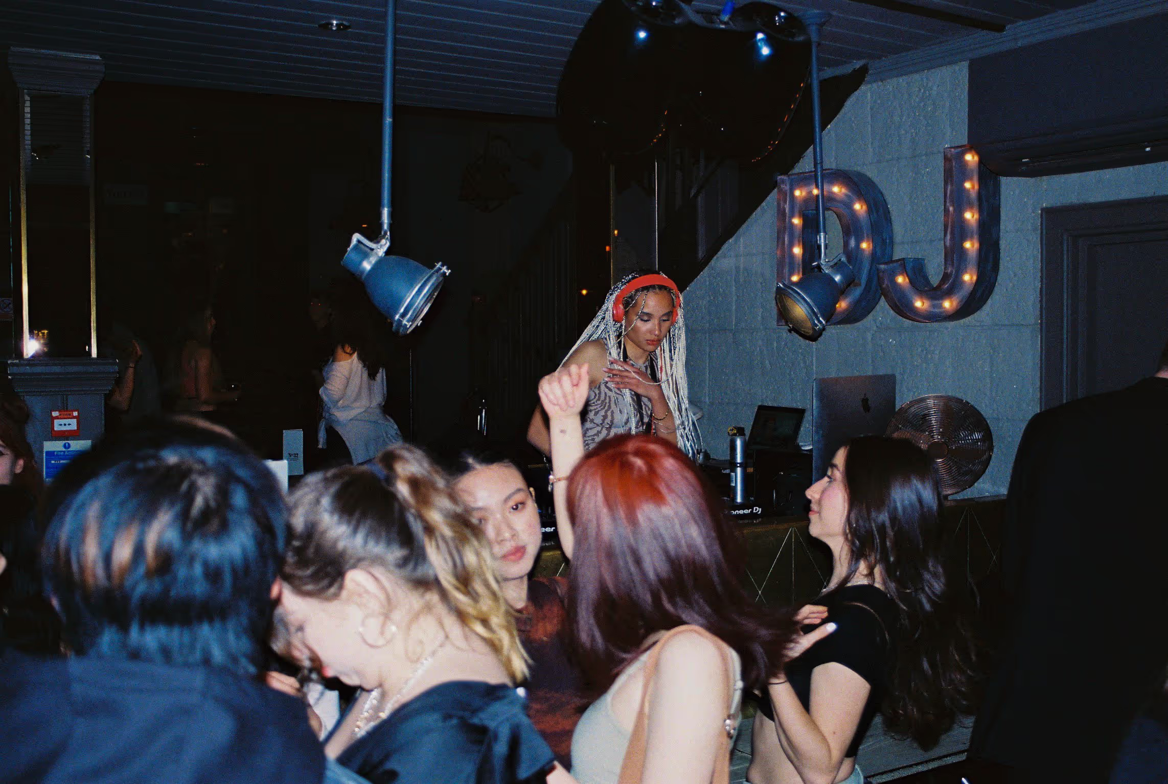 A crowd dancing in front and back of the DJ's deck at the Soirée's launch party in London, UK