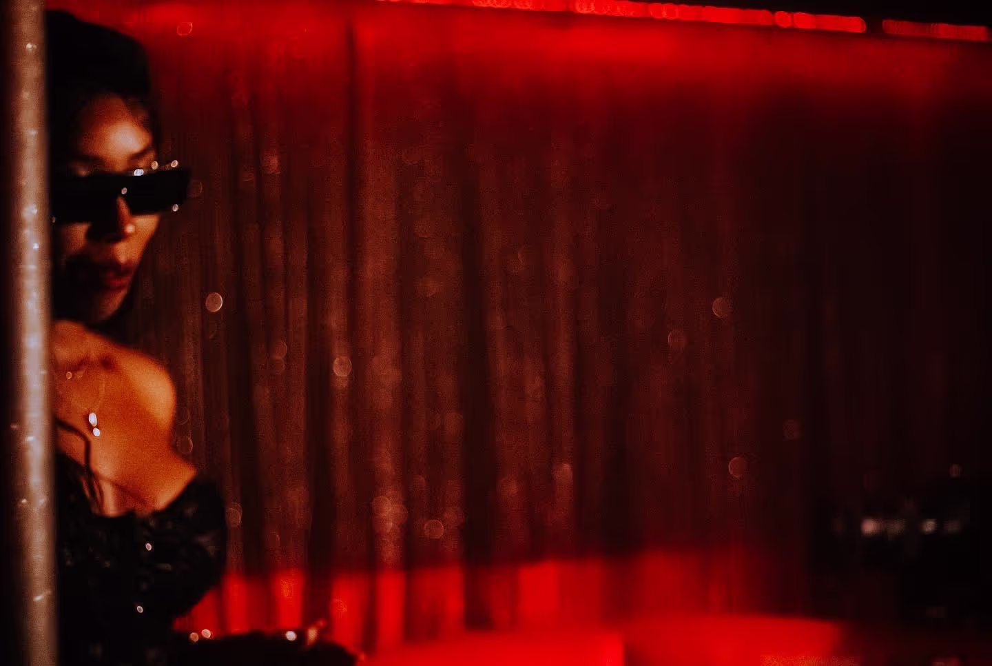 A woman in a black dress and red lights in the background at Soirée's "Red Room" party at Proud Cabaret in Brighton, UK