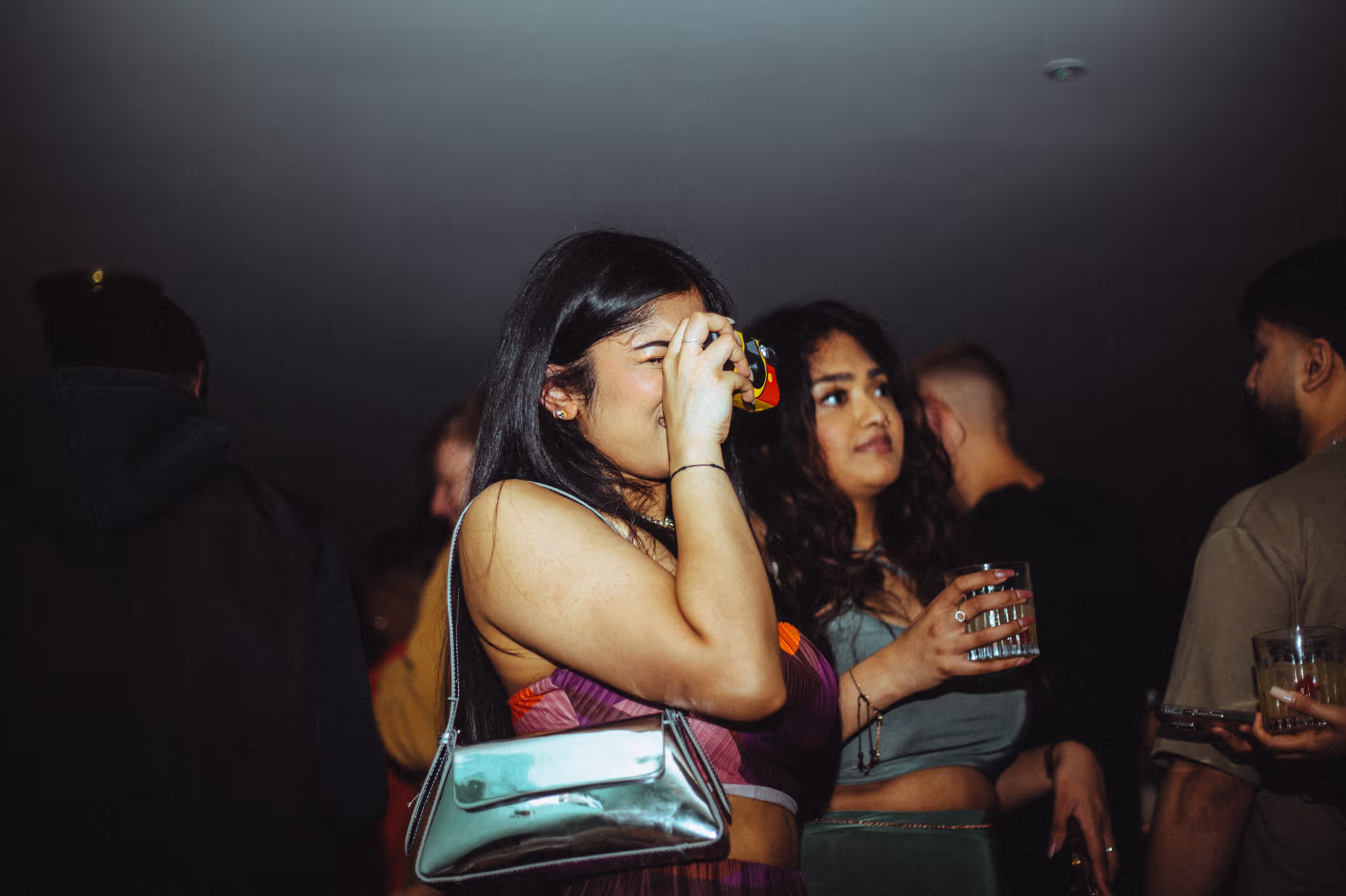 A girl taking a photo with people in the background at Soirée's collaboration party with Brighton Beach House in Brighton, UK