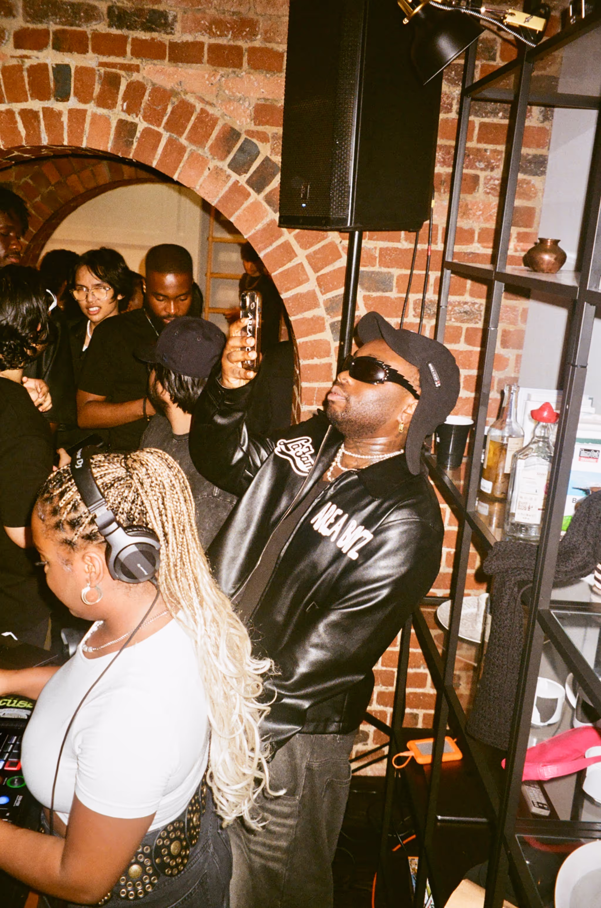 A man taking photos of the DJ and the crowd at Soirée's MONOCHROME House Party vol.2, with a dress code ALL BLACK