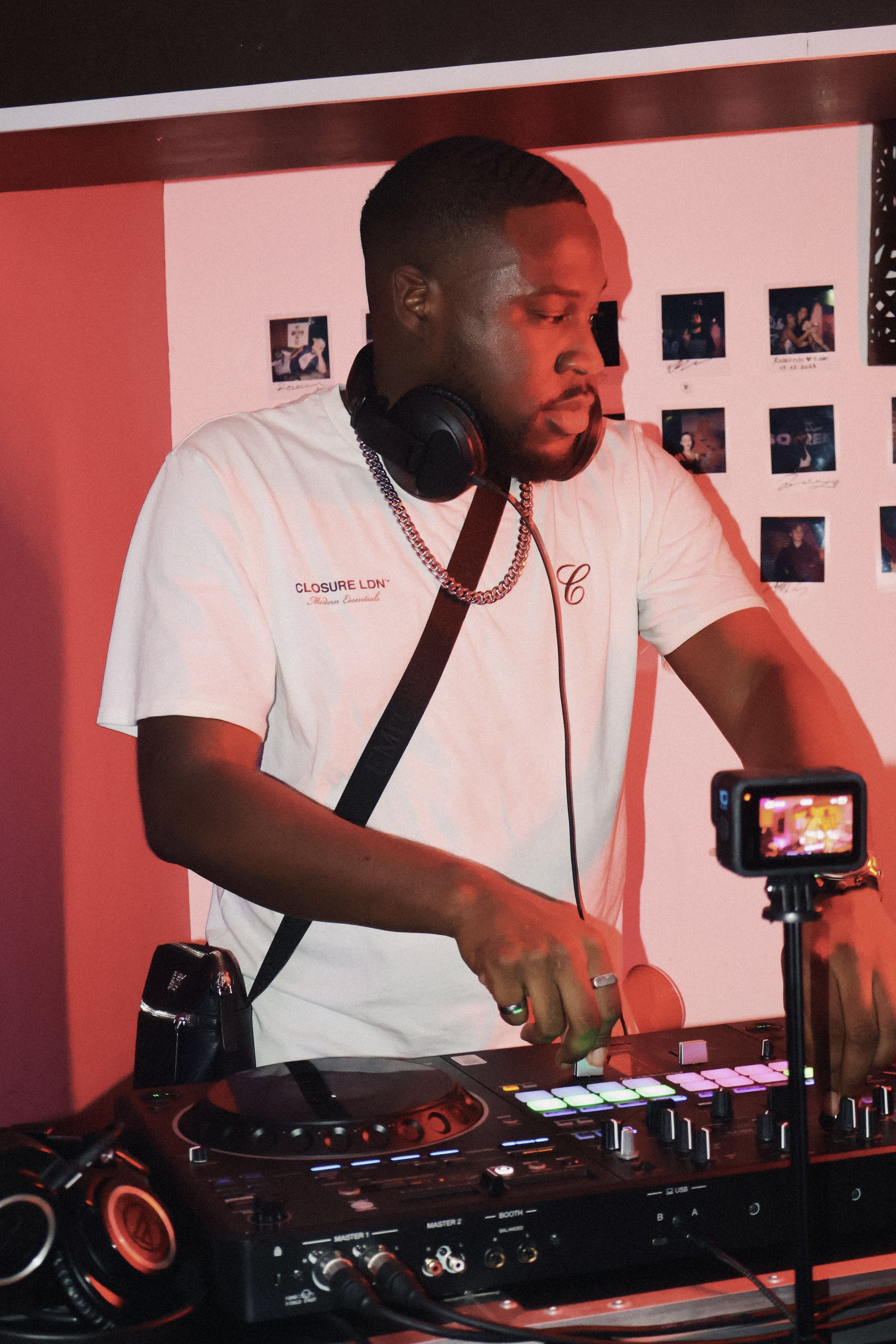 A focused DJ performing his set, and a camera recording in front at Soirée's house party