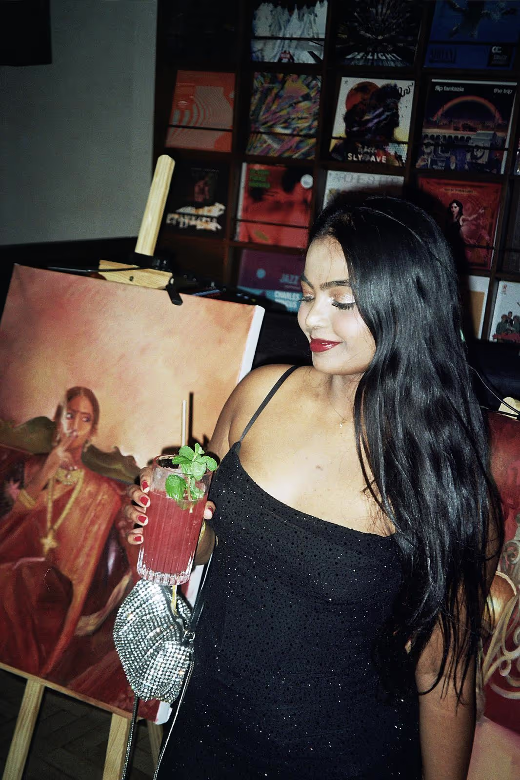 A young woman in a black dress posing with art in the background at the art show by Soirée at Soho Brighton Beach, UK