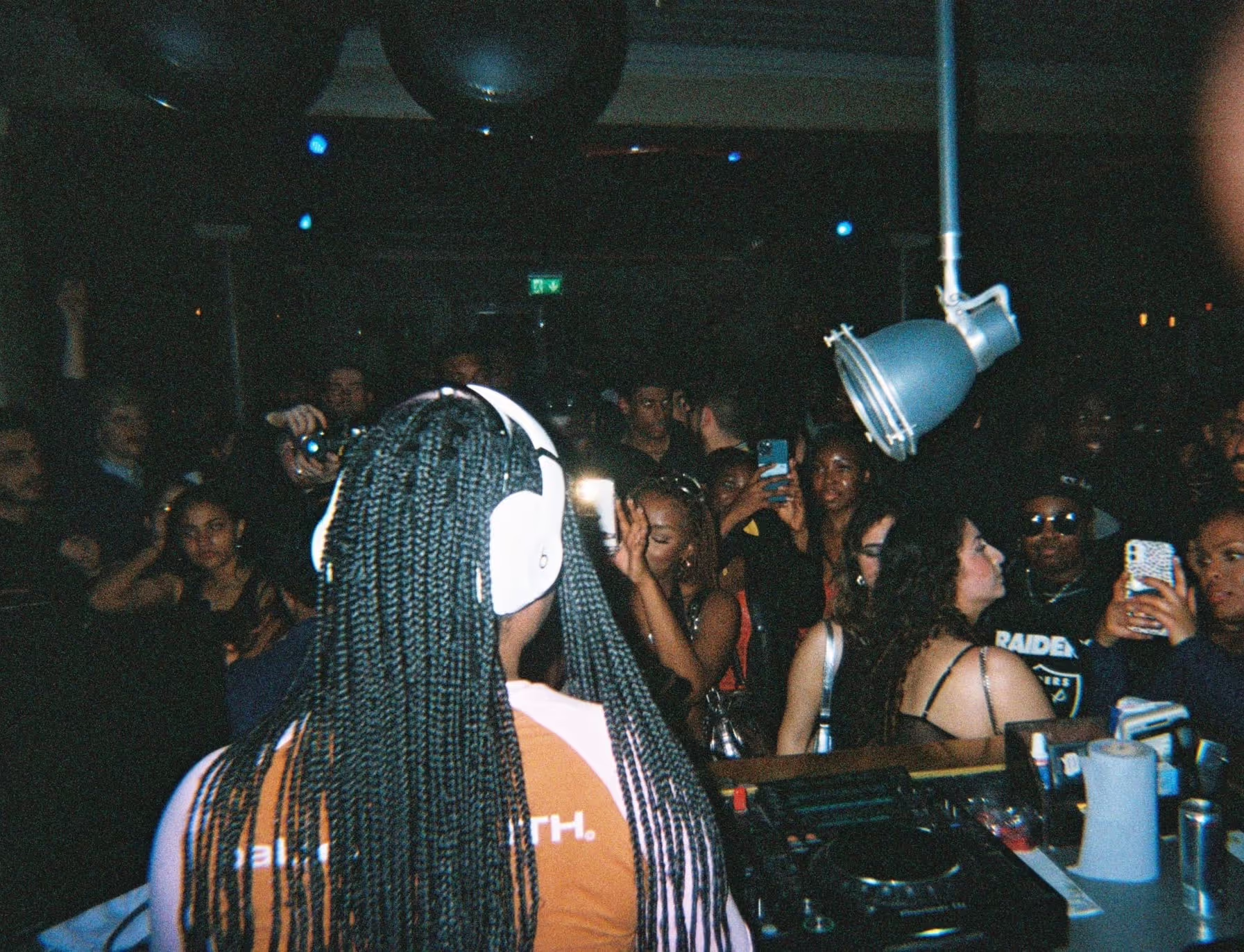 A DJ performing, a dancing crowd in the background taking photos at the Soirée Valentine’s Night event, in London, UK