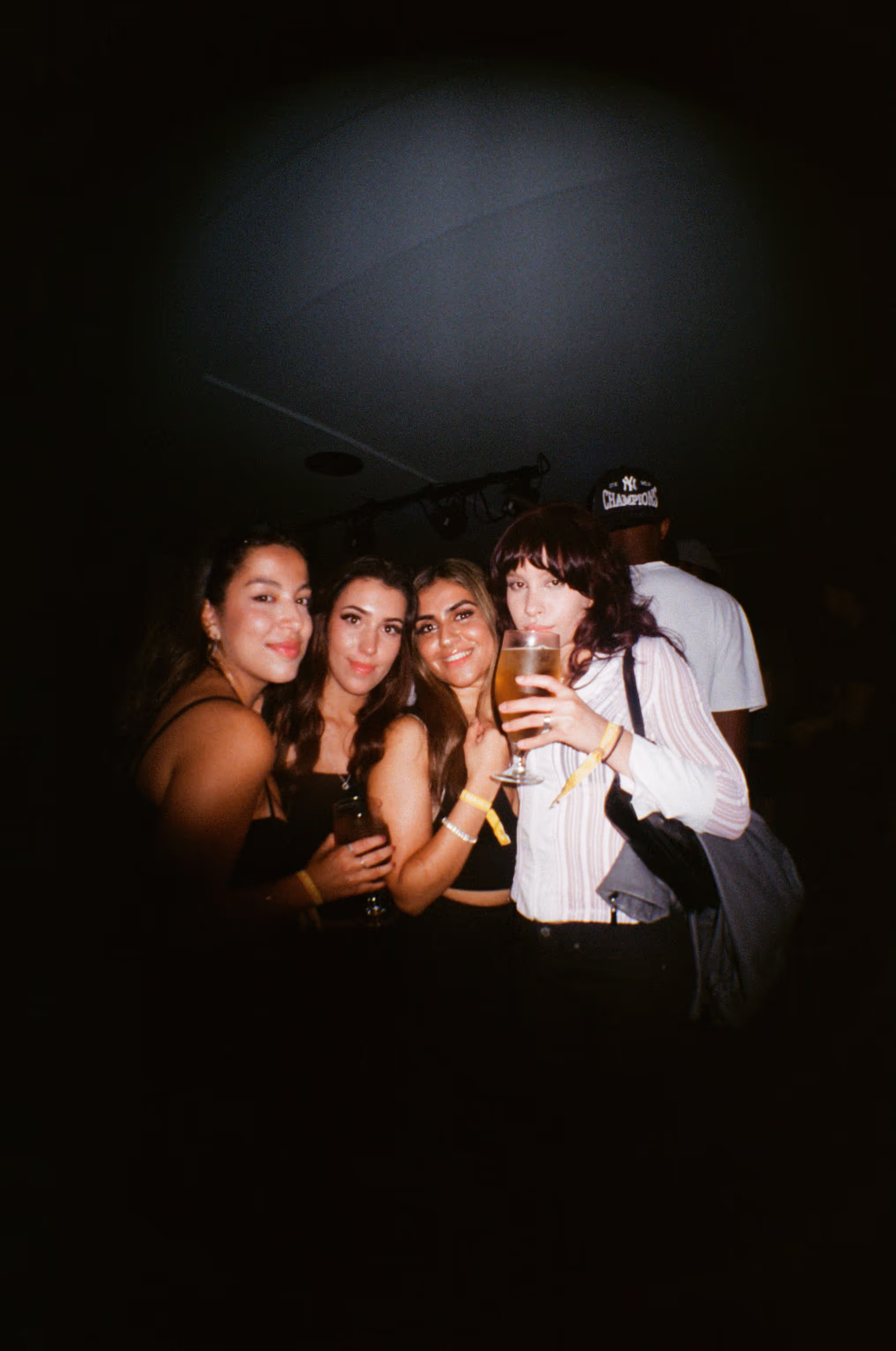 Four girlfriends toasting with drinks and having fun at the Soirée art show and music event at Soho Brighton Beach House, Brighton, UK