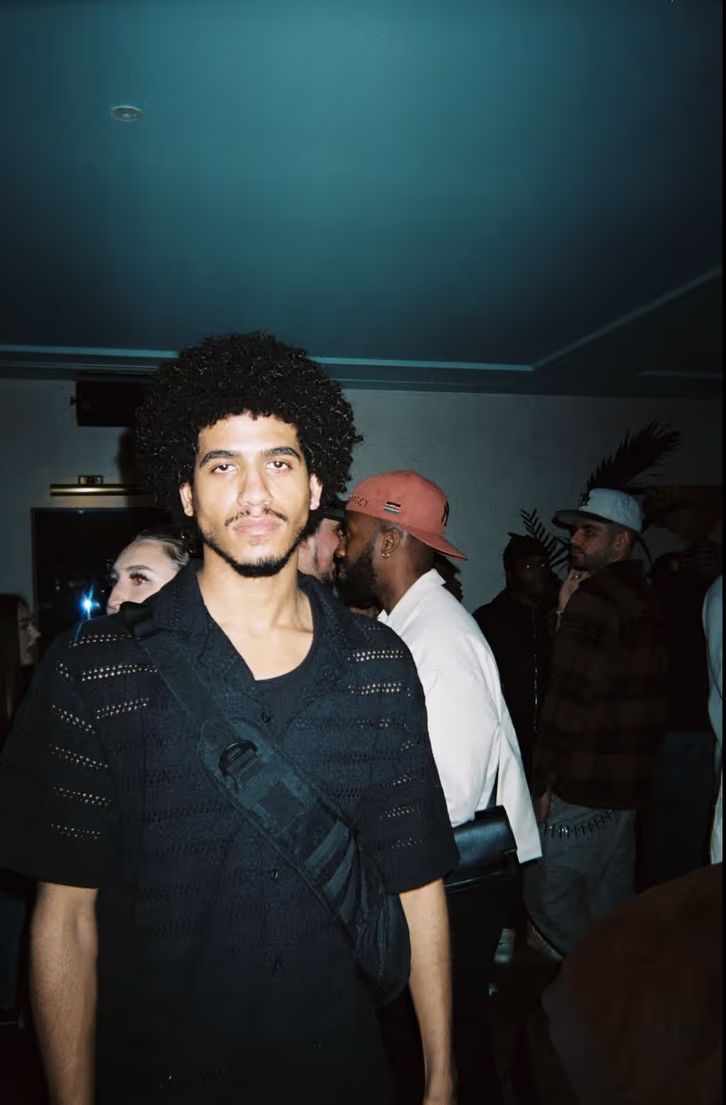 A man posing with the crowd in the background at the Soirée's event in Brighton, UK