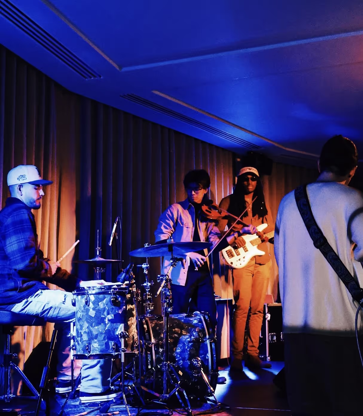 A band of 4 musicians (drums, violin, bass, guitar) performing at the Soirée's event in Brighton, UK